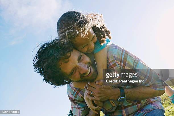 low angle view of father carrying daughter piggyback outdoors - piggyback stock pictures, royalty-free photos & images
