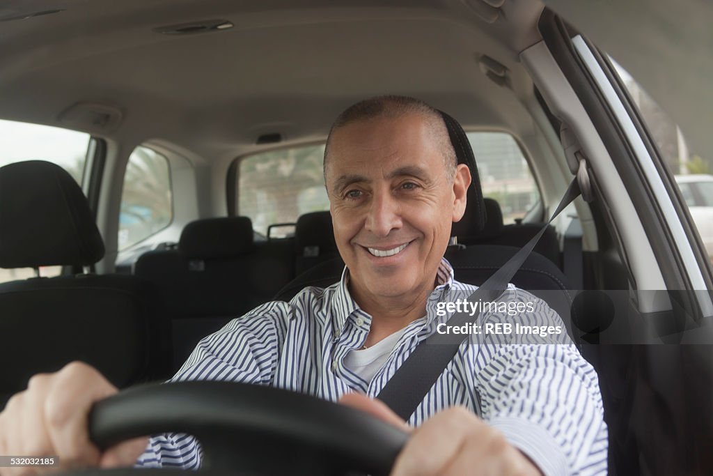 Hispanic senior man driving car