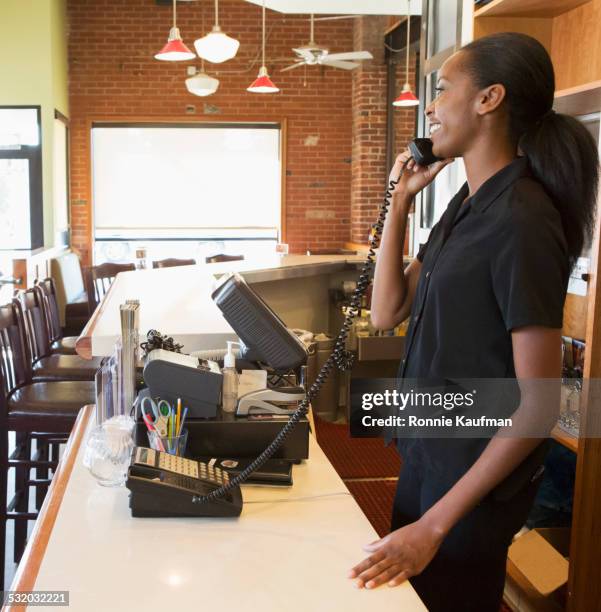 hispanic server talking on telephone in restaurant - hostess stand stock pictures, royalty-free photos & images