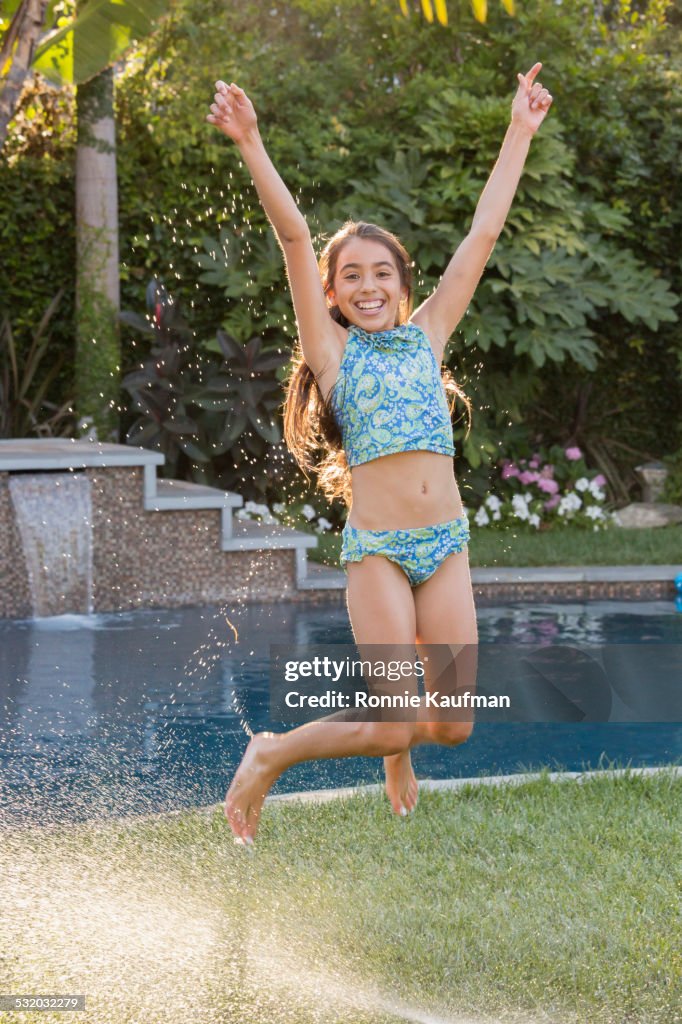 Hispanic girl jumping for joy in backyard