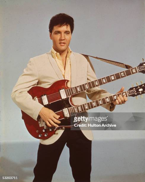 Portrait of American singer and actor Elvis Presley holding a 1965 Gibson EBS-1250 Double Bass , circa 1966. Elvis is seen playing the guitar in his...