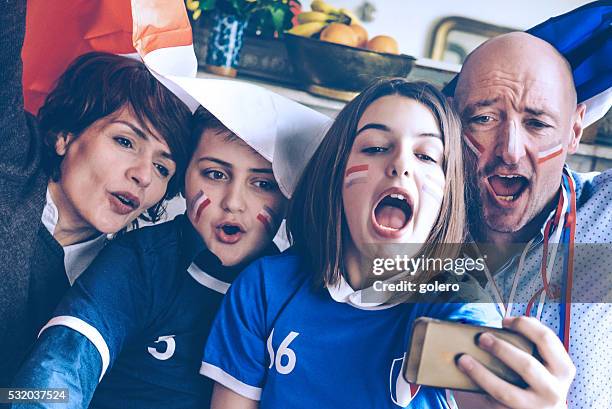 french family with flag watching soccer game on mobile phone - football phone stock pictures, royalty-free photos & images