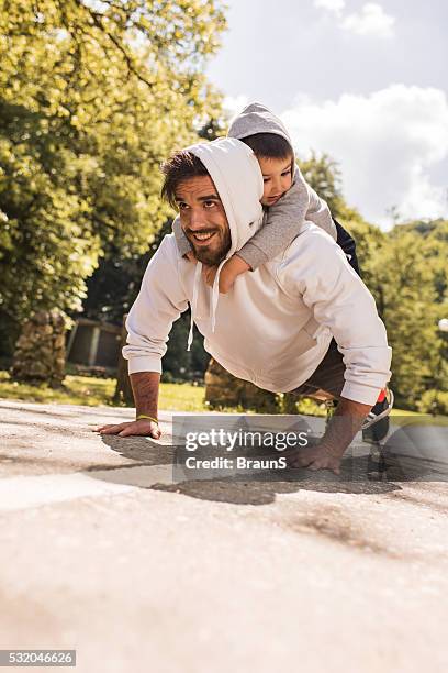 happy father doing push-ups with his little boy in nature. - dad press ups kids stock pictures, royalty-free photos & images