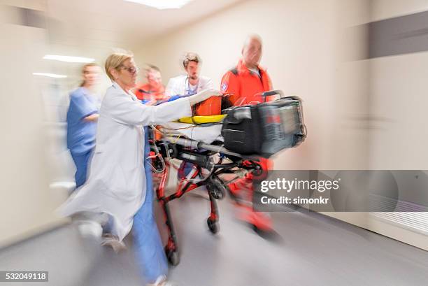 paramedics wheeling patient in hospital - emergency services occupation stockfoto's en -beelden