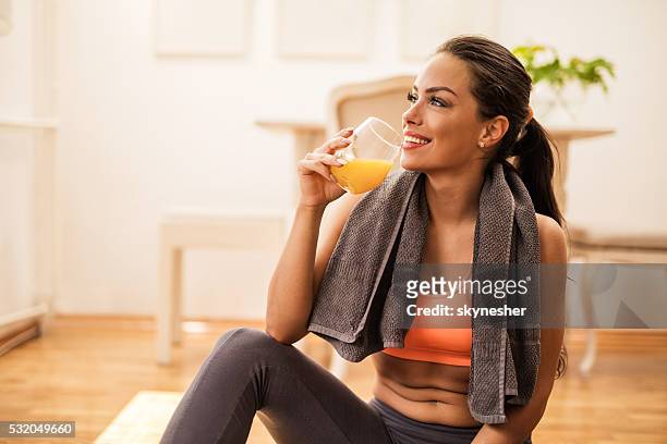 smiling woman drinking orange juice after sports training. - orange juice stock pictures, royalty-free photos & images