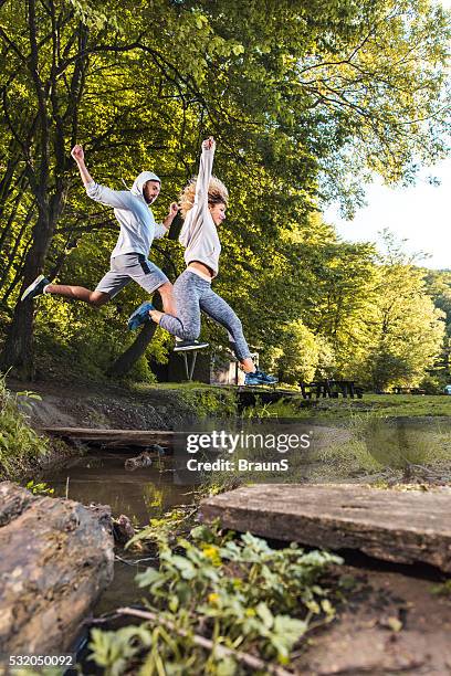 young athletes jumping over the stream in the park. - ditch stock pictures, royalty-free photos & images