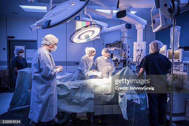 team of surgeons operating on patient in hospital - chirurgie stockfoto's en -beelden