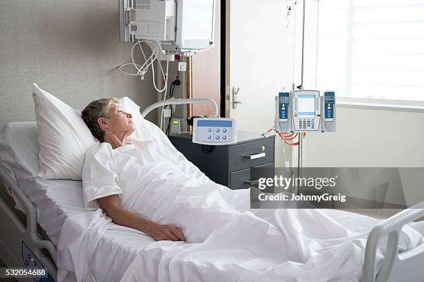 senior woman lying in hospital bed looking away - hospital bed stockfoto's en -beelden