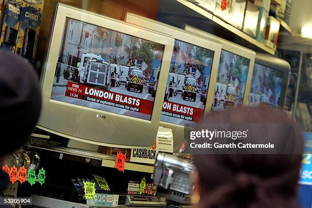 People watch reports on televisions in a shop near Edgware Road station following a series of explosions which ripped through London's underground...