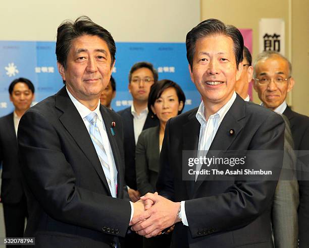 Japanese Prime Minister Shinzo Abe and junior coalition Komeito leader Natsuo Yamaguchi shake hands as the supplementary budget of the support for...