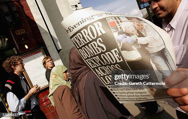 Commuters read newspapers at Edgware Road underground station which show images of the wounded from the bomb blasts which ripped across London's...