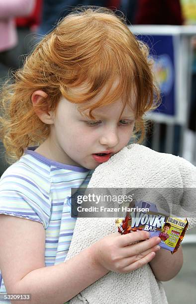 Jessi Dyck samples some Wonka candy during actor Deep Roy's performance dancing on the "Charlie and the Chocolate Factory" movie billboard in...
