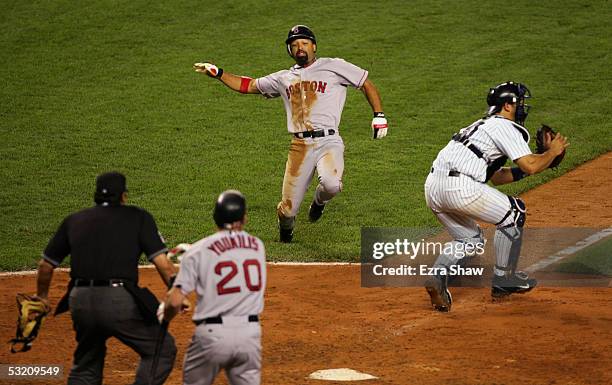 Dave Roberts of the Boston Red Sox slides in to home plate past Jorge Posada of the New York Yankees to tie the game on a hit by Orlando Cabrera in...
