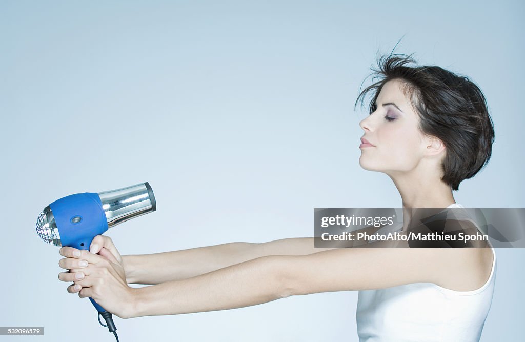 Woman holding out hair dryer, profile