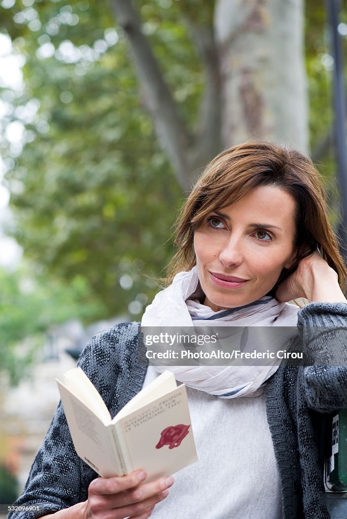 Woman reading paperback book outdoors