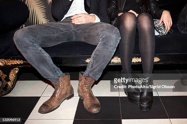young couple sitting side by side at night club - breitbeinig stock-fotos und bilder