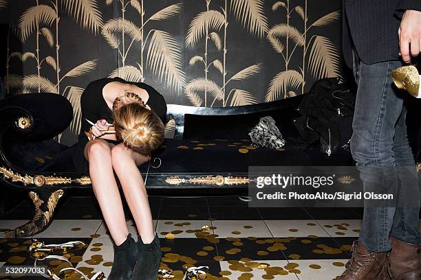 woman resting head on lap after party - confetti floor stockfoto's en -beelden