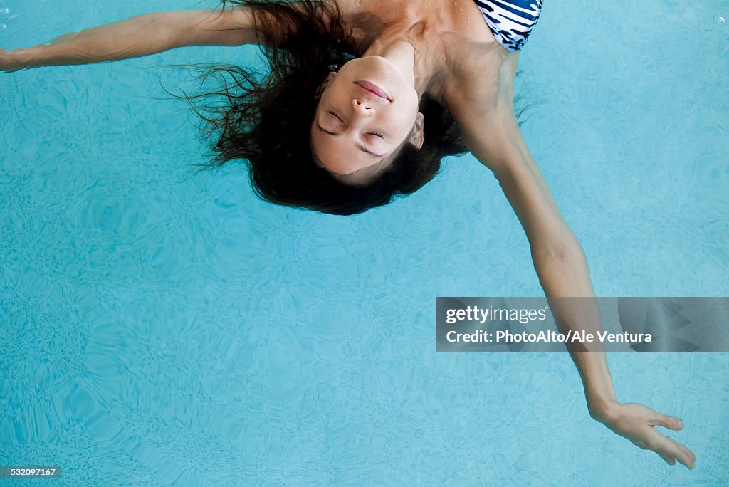 Woman floating in pool with eyes closed