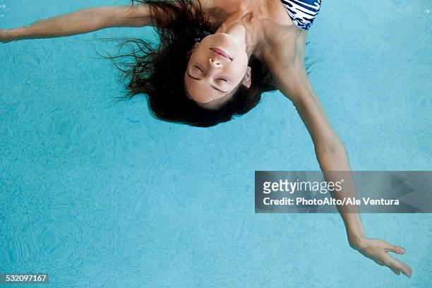 woman floating in pool with eyes closed - ligero fotografías e imágenes de stock