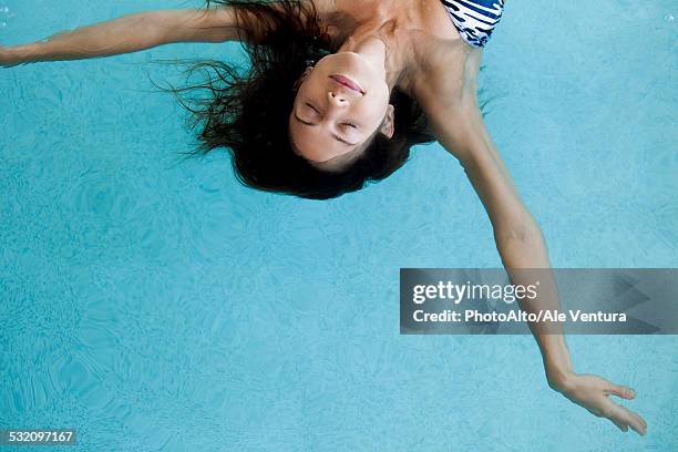 woman floating in pool with eyes closed - tranquility spa stock pictures, royalty-free photos & images