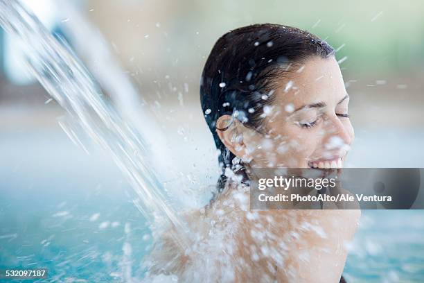 woman relaxing under fountain in pool - health spa stock pictures, royalty-free photos & images