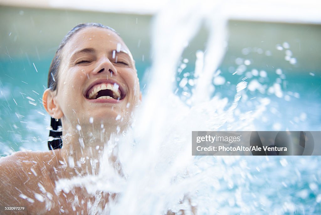 Woman splashing in pool with eyes closed