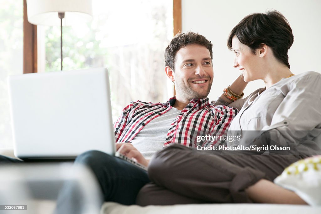 Couple relaxing together on sofa with laptop computer