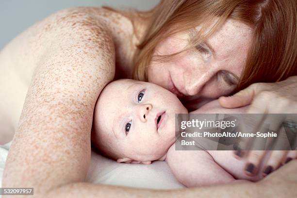 mother lying down, embracing baby - red hair boy and freckles stock-fotos und bilder