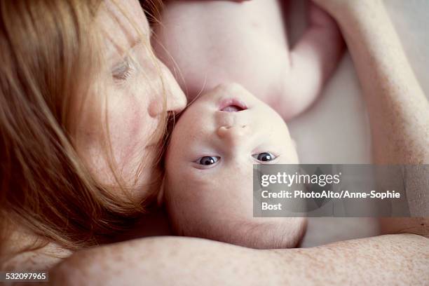 mother lying down, kissing babys cheek, overhead view - baby eltern von oben stock-fotos und bilder