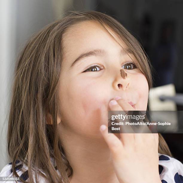 girl with chocolate smeared on her nose, licking fingers - chocolate square stock pictures, royalty-free photos & images