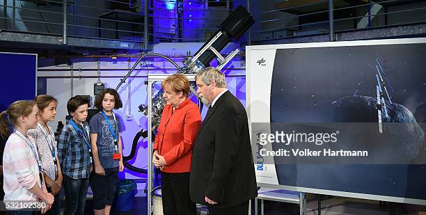 German Chancellor Angela Merkel watches an experiment in the DLR_School_Lab Cologne with the head teacher Richard Braeucker and some pupils during a...
