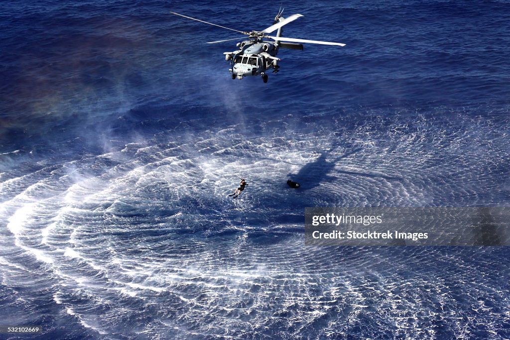 An MH-60S Seahawk lowers a rescue swimmer into the water.