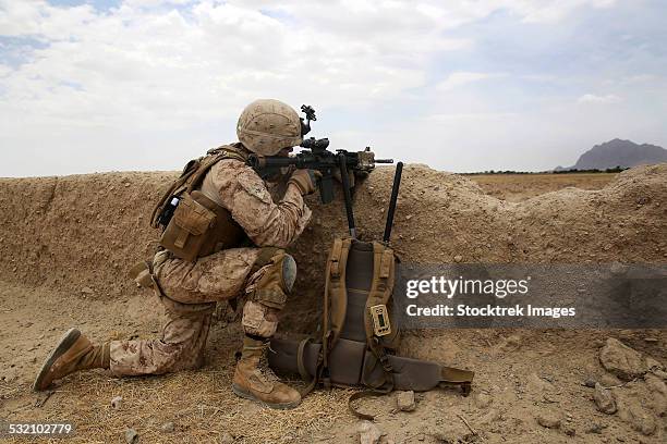 u.s. marine provides security from behind a mud wall. - ejército nacional afgano fotografías e imágenes de stock