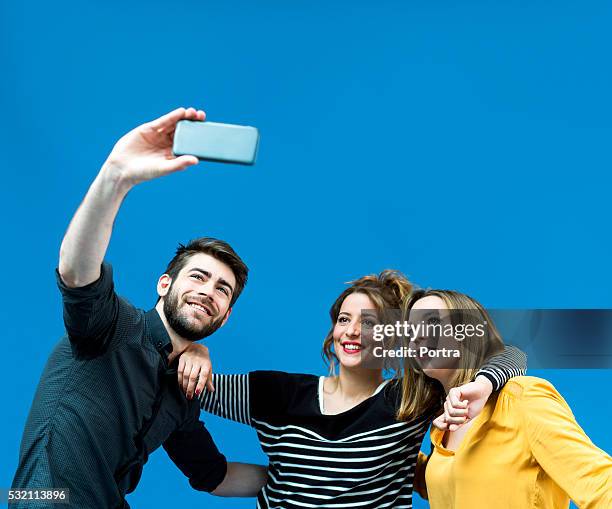 happy friends taking selfie from mobile phone against blue screen - blue screen stock pictures, royalty-free photos & images