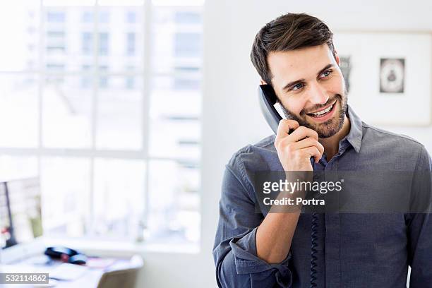 happy businessman using landline phone in office - telefonlur bildbanksfoton och bilder