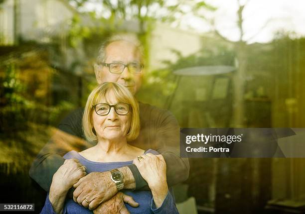 loving senior couple seen through glass window - senior looking at camera stock pictures, royalty-free photos & images