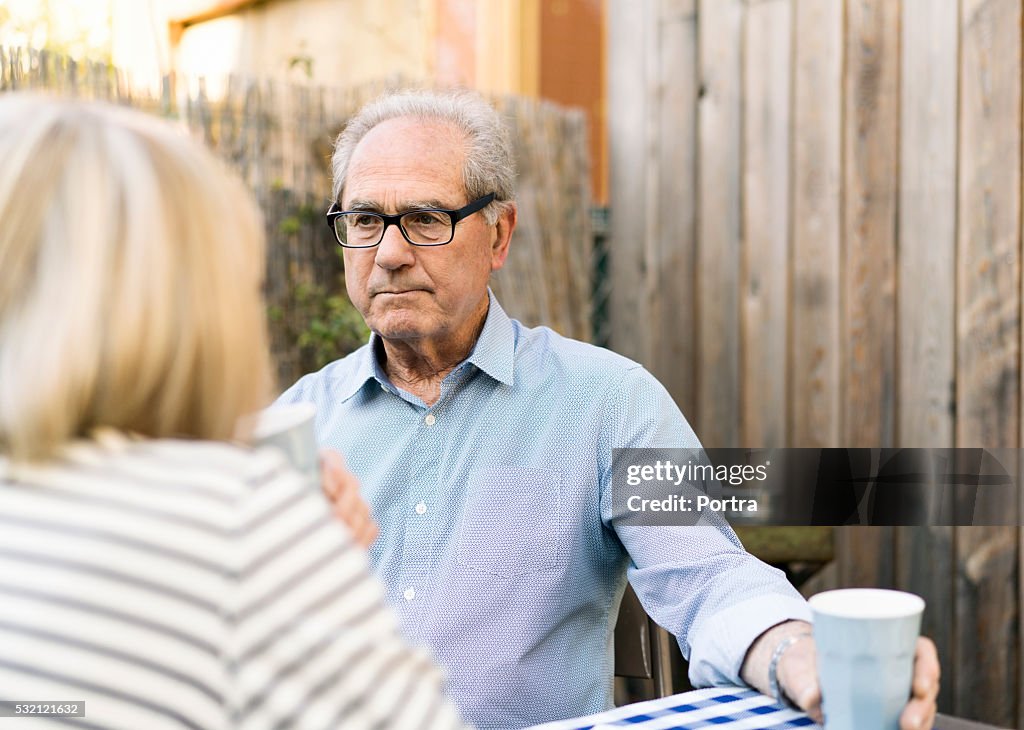 Thoughtful senior man with woman in backyard