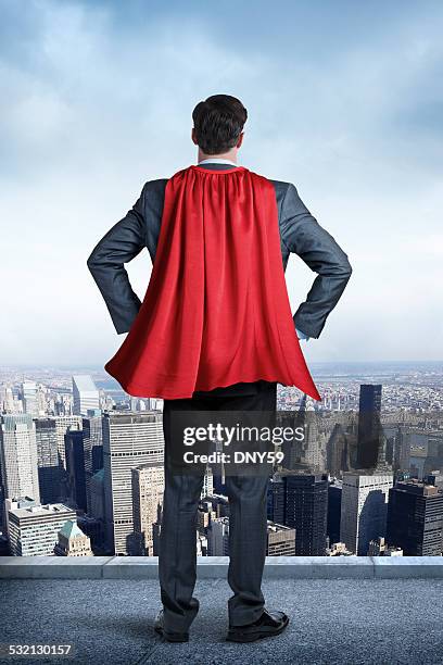 superheld geschäftsmann mit red cape blick in die stadt - cape stock-fotos und bilder