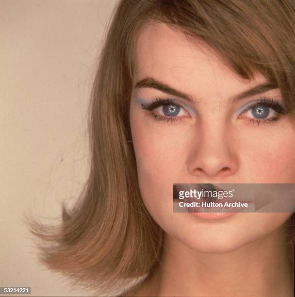 English fashion model Jean Shrimpton looks at the camera, wearing heavy blue eyeshadow, 1960s.