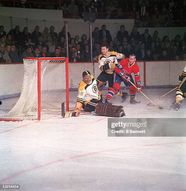 Canadian pro hockey player Bernie Parent, goalie for the Boston Bruins, appears to make a kick save as Montreal Canadiens forward Dave Balon moves in...