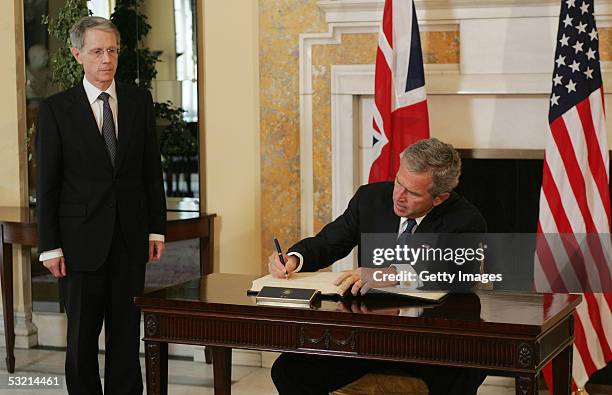 President George W. Bush signs the book of condolences at the British embassy as Ambassador Sir David Manning looks on, July 8, 2005 in Washington,...