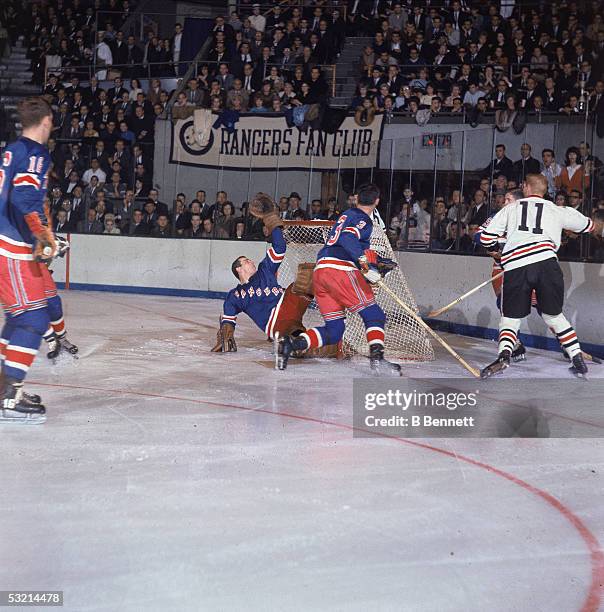 Canadian pro hockey player Ed Giacomin, goalie for the New York Rangers, takes a swipe at the puck as it sails over the crossbar and Ranger...