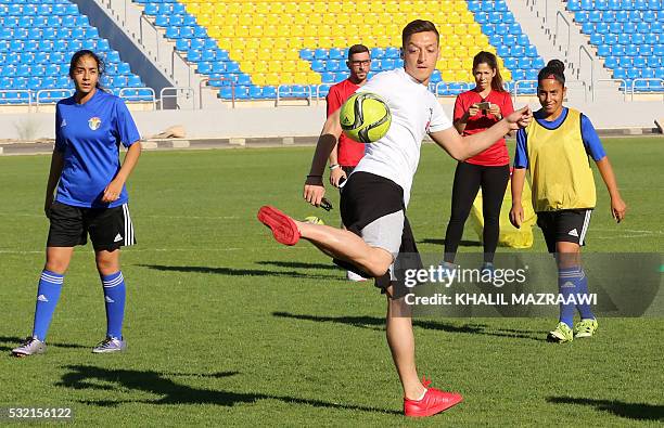 Arsenal's German midfielder Mesut Ozil plays with members of the women's U-17 Jordanian national football team during a training session on May 18,...