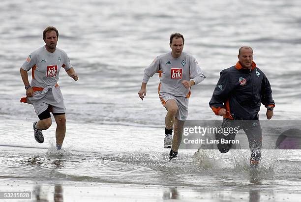 Assistant-Coach Mathias Hoenerbach, Doctor Goetz Dimanski and Coach Thomas Schaaf run on the beach during a training session at Werder Bremen...