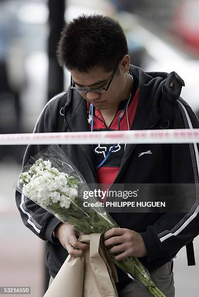 London, UNITED KINGDOM: A man holds flowers in memory of the victims of the bomb attacks, near the area where the bus exploded in Tavistock square in...