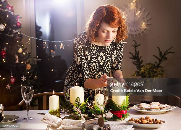 woman lights candles on christmas dining table. - christmas decoration home stock pictures, royalty-free photos & images