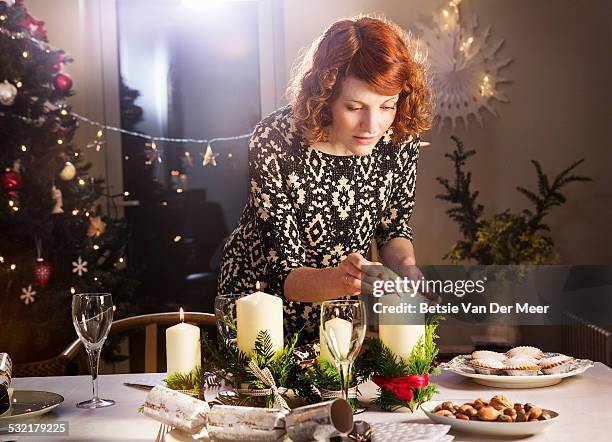 woman lights candles on christmas dining table. - dukning bildbanksfoton och bilder
