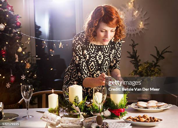 woman lights candles on christmas dining table. - table decoration 個照片及圖片檔