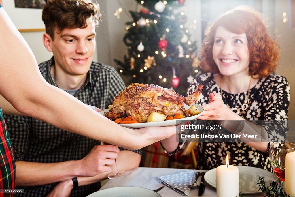 Woman takes plate with turkey at Christmas dinner.