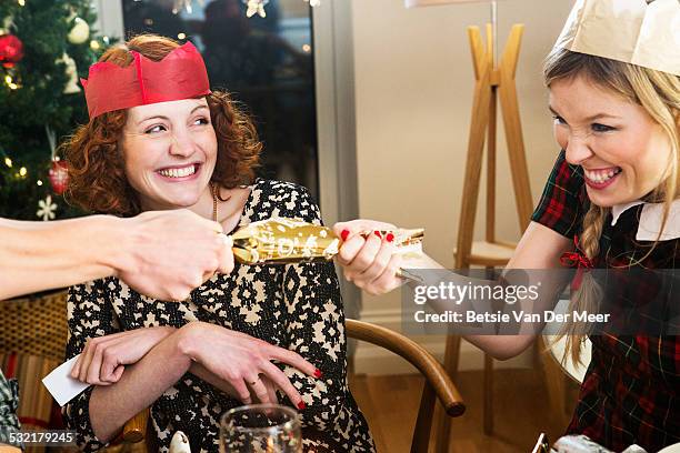 friends pulling crackers at christmas dinner party - christmas cracker stock pictures, royalty-free photos & images